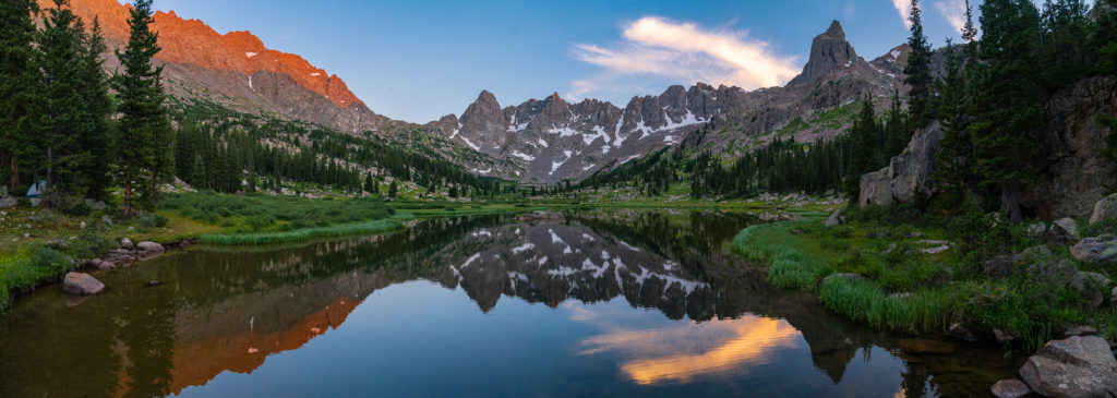 mountain range with alpine lake in foreground during sunset